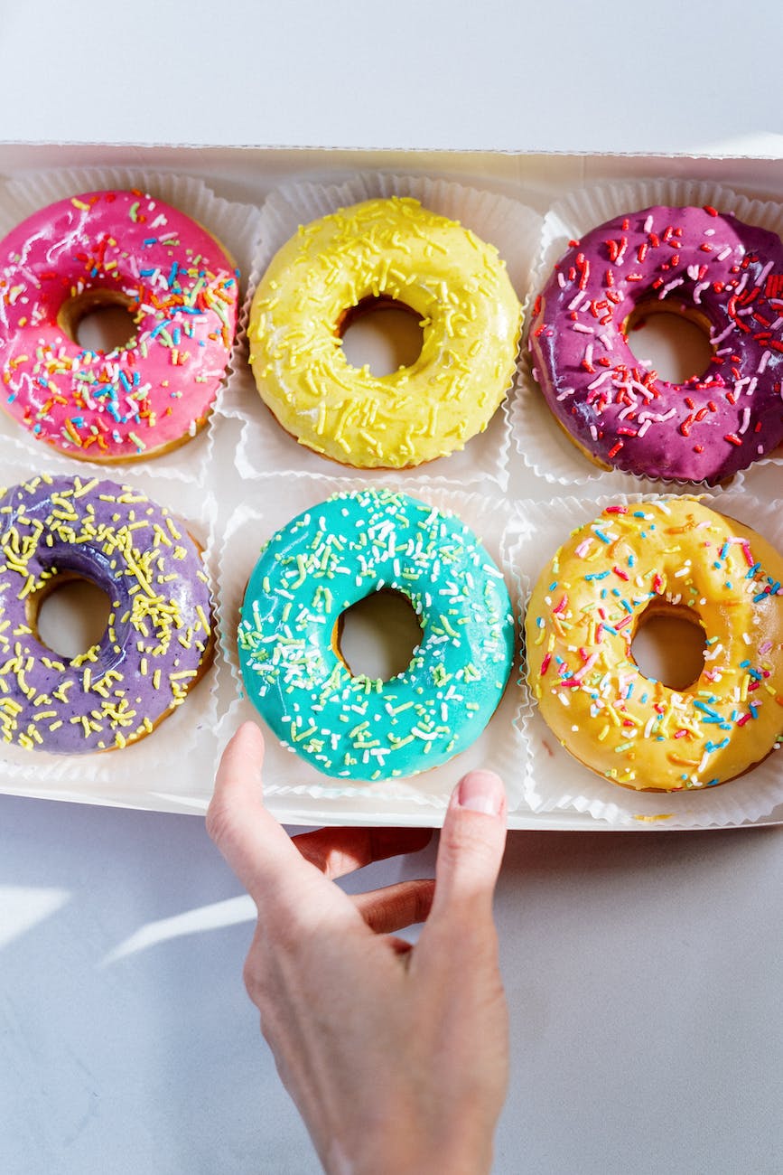 6 donuts de colores brillantes y apetitosos, dispuestos en una fila, con glaseado de diferentes sabores y espolvoreados con chispas de colore